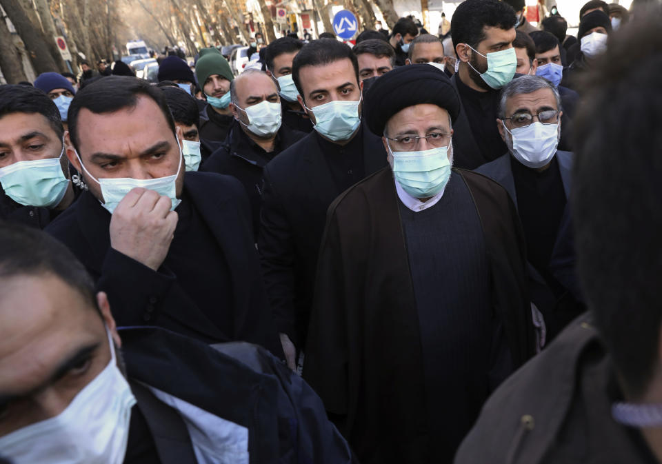 President Ebrahim Raisi, center right, attends a funeral procession for unknown Iranian soldiers who were killed during the 1980-88 Iran-Iraq war, whose remains were recently recovered from former battlefields, in Tehran, Iran, Thursday, Jan. 6, 2022. Thousands of mourners poured into the streets of Iranian cities on Thursday for the mass funeral of 250 victims of the war, a testament to the brutal conflict's widespread scale and enduring legacy 35 years later. (AP Photo/Vahid Salemi)