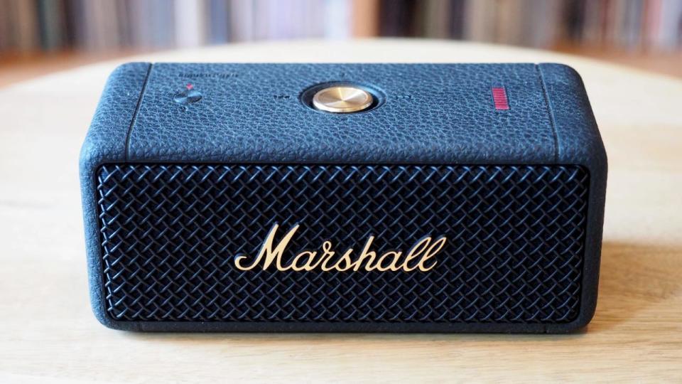 The marshall emberton II speaker sits on a table; there's a bunch of vinyl in the background. 