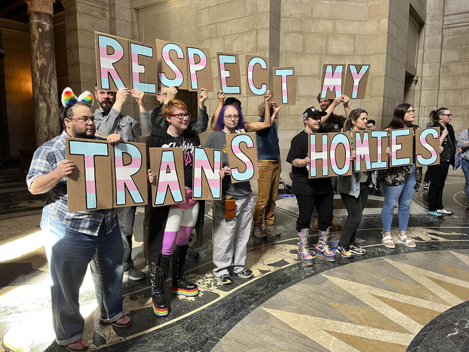 A group of around 200 people who turned out for a rally inside the Nebraska State Capitol hold up signs in support of the transgender community, Friday, March 24, 2023 in Lincoln, Neb. The rally was held to protest the advancement of a bill Thursday that would ban gender-affirming care for minors, as well as a bill that would criminalize allowing minors to attend drag shows. (AP Photo/Margery Beck)