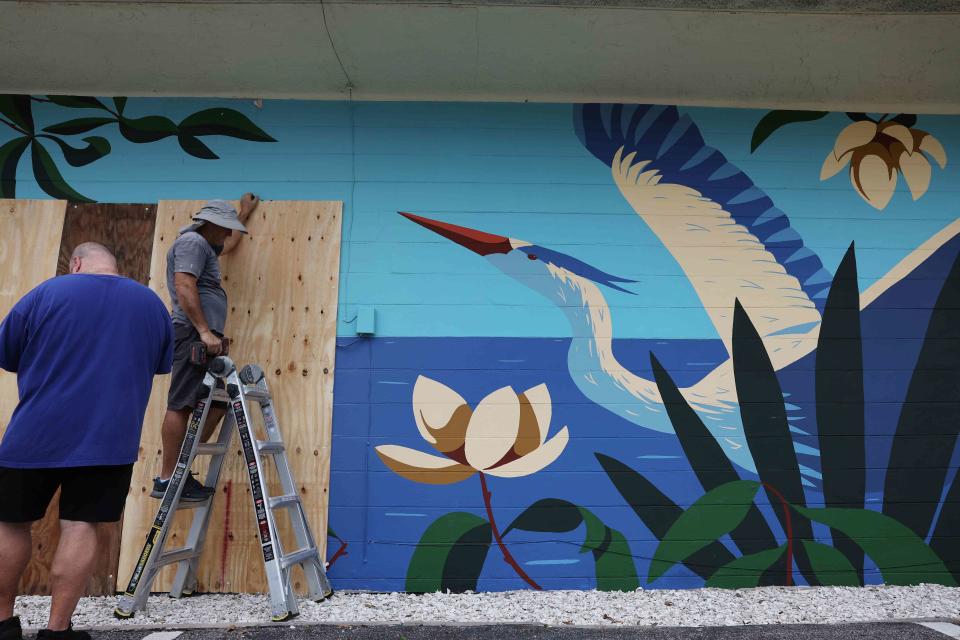 <p>Photo by Spencer Platt / Getty Images</p> Men board up a bar in St. Petersburg, Fla., on Monday in preparation for Hurricane Milton. 