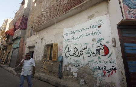 Ahmed El-Gamal, the father of Samir, a 10-year-old Egyptian boy who died during clashes between supporters and opponents of deposed Islamist President Mohamed Mursi, walks in front his house with graffiti in Suez May 25, 2014. REUTERS/Stringer