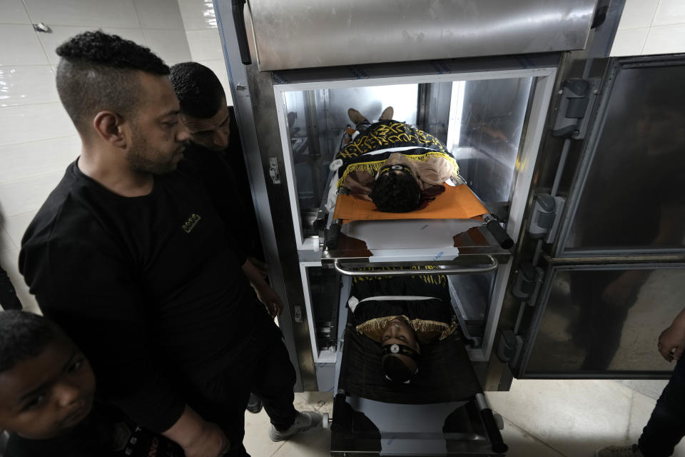 Relatives take a last look at Ahmed Assaf, 19, top, and Rani Qatanat, 24, draped in the flag of Islamic Jihad, two Palestinians killed by Israeli forces in Qabatiya, near the West Bank city of Jenin, Wednesday, May 10, 2023. The Israeli military said that Palestinian gunmen opened fire at troops in the Palestinian town of Qabatiya in the northern West Bank during an army raid. Troops returned fire, killing the two men, and confiscated their firearms, it said. (AP Photo/Majdi Mohammed)