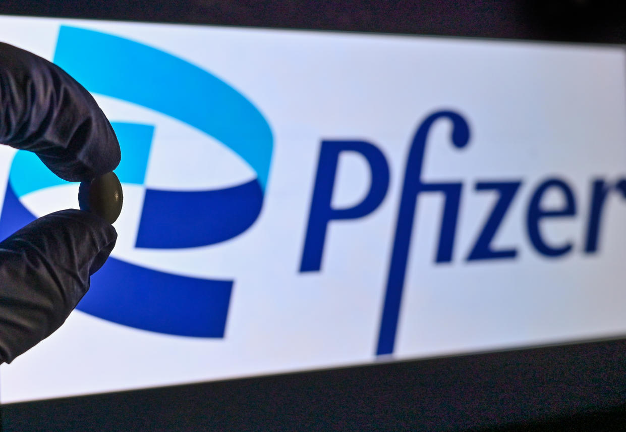 A medical tablet seen in front of the Pfizer logo.