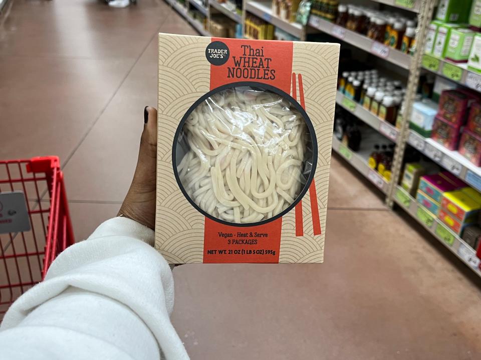 hand holding up a box of trader joe's thai wheat noodles at trader joes