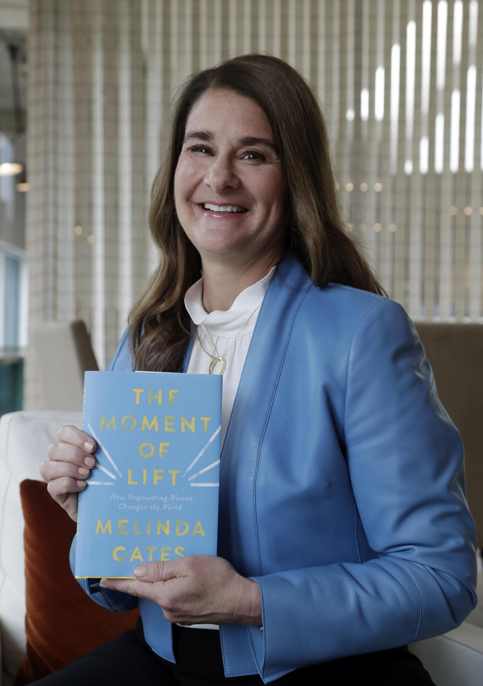 In this photo taken Thursday, April 18, 2019, Melinda Gates poses for a photo with her new book, "The Moment of Lift," in Kirkland, Wash. Her new book is a memoir from the former Microsoft tech business executive, outspoken feminist and public supporter of the MeToo movement. The Associated Press reviewed an advanced copy of the book ahead of its release Tuesday. (AP Photo/Elaine Thompson)