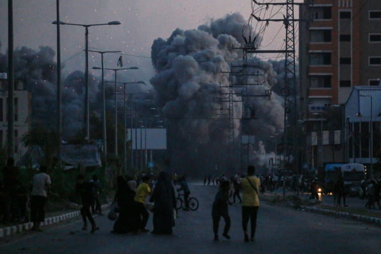 Palestinians watch smoke billowing following an Israeli air strike in Deir al-Balah (Bashar TALEB)