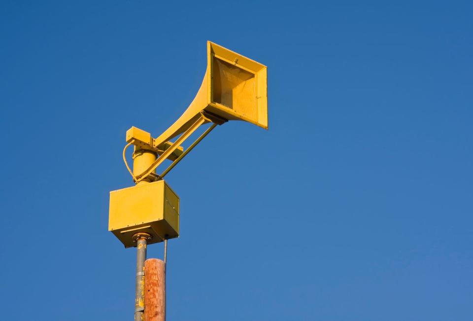 Outdoor warning siren in western Nebraska against a sunny blue sky.