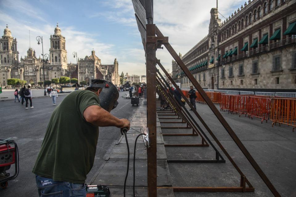 Un soldador colocando vallas metálicas para proteger el Palacio Nacional en la Ciudad de México ante las marchas del
