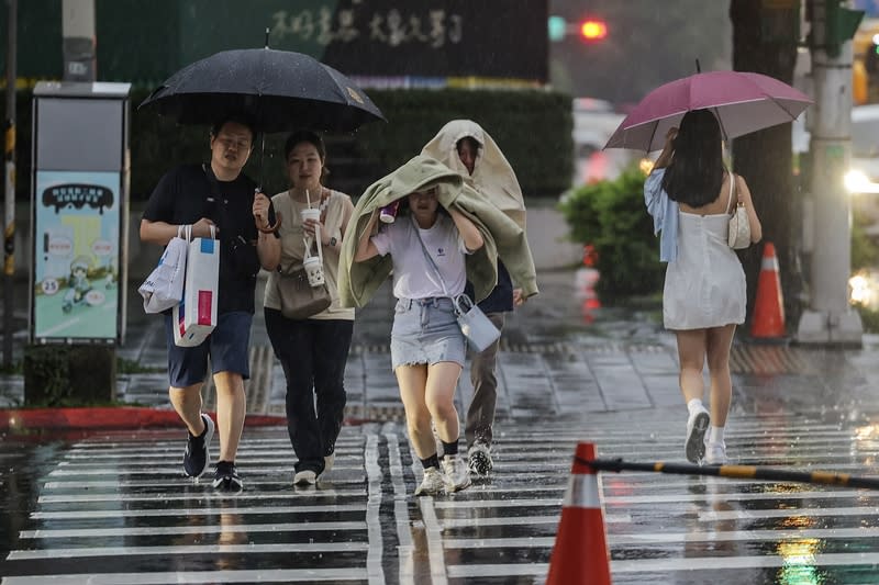 氣象署發布大雨特報（3） 中央氣象署16日下午發布大雨特報，並針對新北市7 處、屏東縣2處發布山區暴雨災防告警；另外北北 基、高屏地區慎防大雷雨。圖為台北市信義區行人以 外套遮擋雨勢，快步過馬路。 中央社記者裴禛攝  113年6月16日 