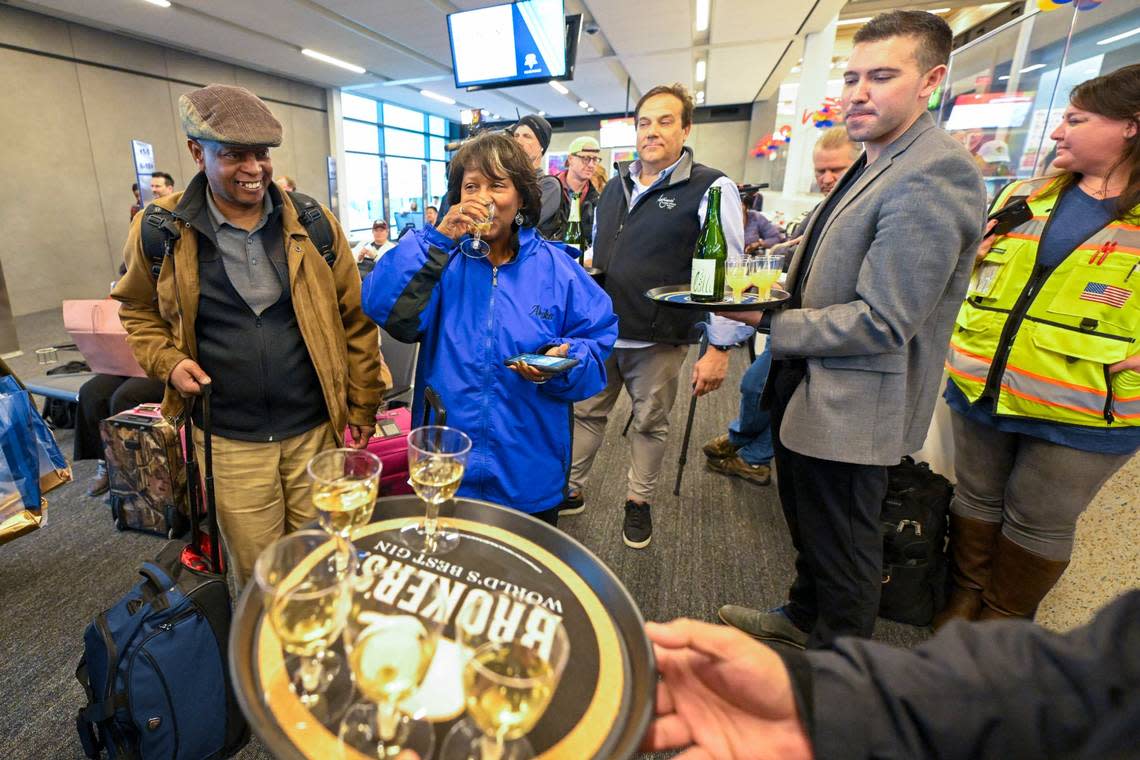 Amania Drane of Darien, Illinois, in blue coat, enjoyed a glass of champagn after arriving from Chicago on the first plane to land at the new single terminal on Tuesday, Feb. 28, 2022, at Kansas City International Airport.