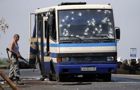 An armed pro-Russian separatist stands near a bus riddled with bullet holes at a checkpoint on the outskirts of Donetsk, August 13, 2014. REUTERS/Sergei Karpukhin