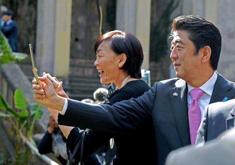 Japanese Prime Minister Shinzo Abe (R) and his wife Akie Abe (L) take pictures of lions at the National Palace in Addis Ababa on January 14, 2014