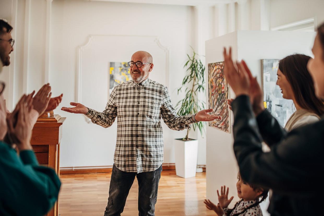 People applauding mature male artist at gallery opening in Serbia