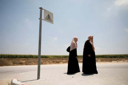 Palestinian women stand next to a road sign at the Israeli side of Erez crossing, on the border with Gaza