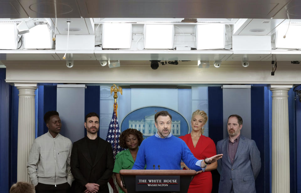 FILE - Jason Sudeikis, fourth from left, who plays the title character in the Apple TV+ series "Ted Lasso," joins White House press secretary Karine Jean-Pierre, third from left, and fellow cast members, from left, Toheeb Jimoh, Brett Goldstein, Hannah Waddingham and Brendan Hunt, during the daily media briefing at the White House in Washington, March 20, 2023. Today, loneliness plays out on streaming TV all the time in the forms of shows like “Ted Lasso.” In March, Sudeikis, the show's creator and star, appeared with his cast at the White House to talk about the issue that the show is, more about than ever: mental health. (AP Photo/Susan Walsh, File)