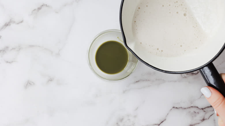 Pouring milk into cup with matcha