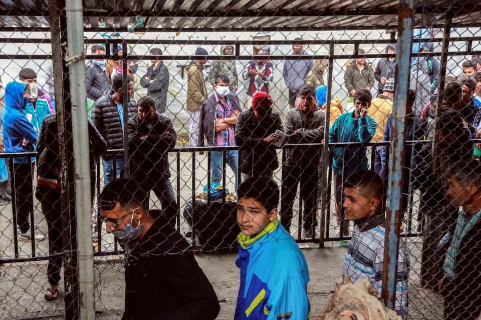 Migrants and refugees, some wearing facemasks for protective measures, queue in a makeshift camp next to the Moria camp on the Greek island of Lesbos on April 2, 2020. - Over 20 coronavirus cases were found in a camp near Athens this week. At the camp of Moria on the island of Lesbos, both doctors and migrants say health precautions are not much help in a facility that is so badly overcrowded. The novel coronavirus could spread faster in overcrowded refugee and displaced persons camps than it has anywhere else so far, warned the International rescue Committee. (Photo by Manolis LAGOUTARIS / AFP) (Photo by MANOLIS LAGOUTARIS/AFP via Getty Images)