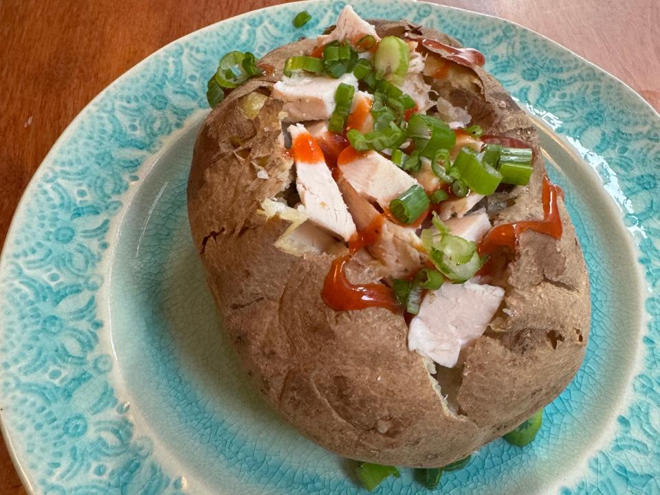Baked potato topped with chicken, chives, and hot sauce