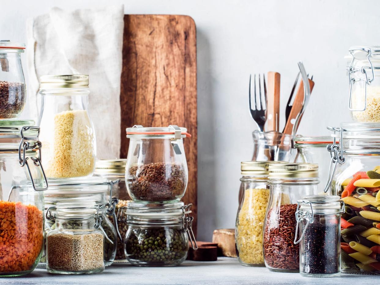 Stocks or set of cereals, pasta, groats, organic legumes and useful seeds in glass jars. Vegan source of protein and energy resources. Healthy vegetarian food. Domestic life scene. Gray kitchen table. Selective focus