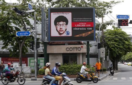 People ride their motorcycles past a digital billboard showing a sketch of the main suspect in Monday's attack on Erawan shrine, in Bangkok, Thailand, August 23, 2015. REUTERS/Chaiwat Subprasom