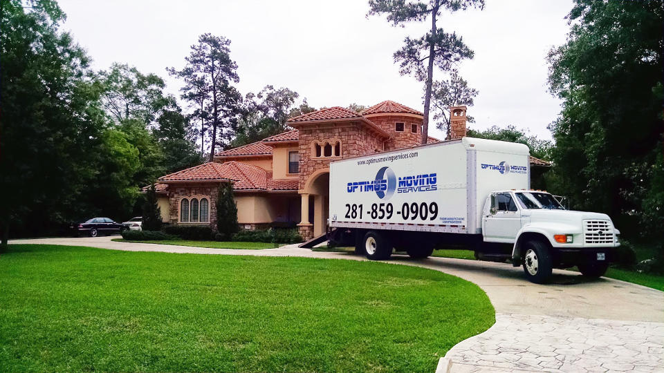 An Optimus Moving Services truck sits outside a home