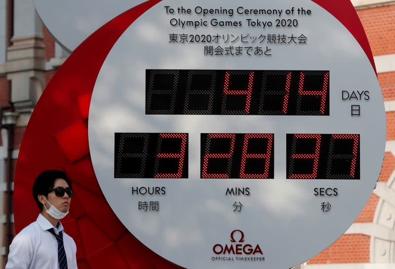 FILE PHOTO: A man wearing a protective mask walks past a countdown clock for the Tokyo 2020 Olympic Games amid the coronavirus disease (COVID-19) outbreak in Tokyo