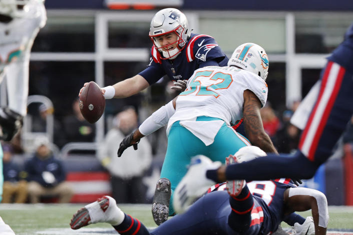 New England Patriots quarterback Mac Jones (10) reacts while pressured by Miami Dolphins linebacker Elandon Roberts (52) during the first half of an NFL football game, Sunday, Jan. 1, 2023, in Foxborough, Mass. (AP Photo/Michael Dwyer)