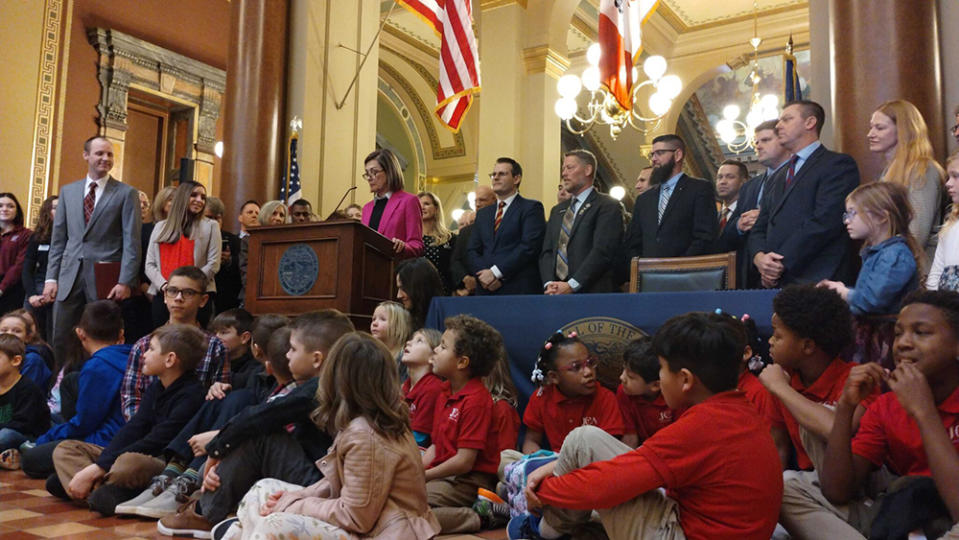 Gov. Kim Reynolds, surrounded by lawmakers and school children, speaks in the Capitol rotunda before signing her private-school scholarship legislation Jan. 24, 2023. (Robin Opsahl/Iowa Capital Dispatch)