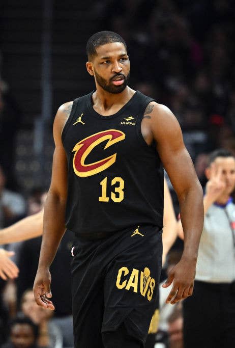 Tristan Thompson in a Cavaliers jersey with the number 13 stands on a basketball court. Other players, including Merrill with jersey number 5, are in the background