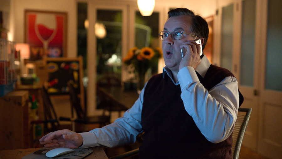 a man on the phone looks shocked while looking at the computer