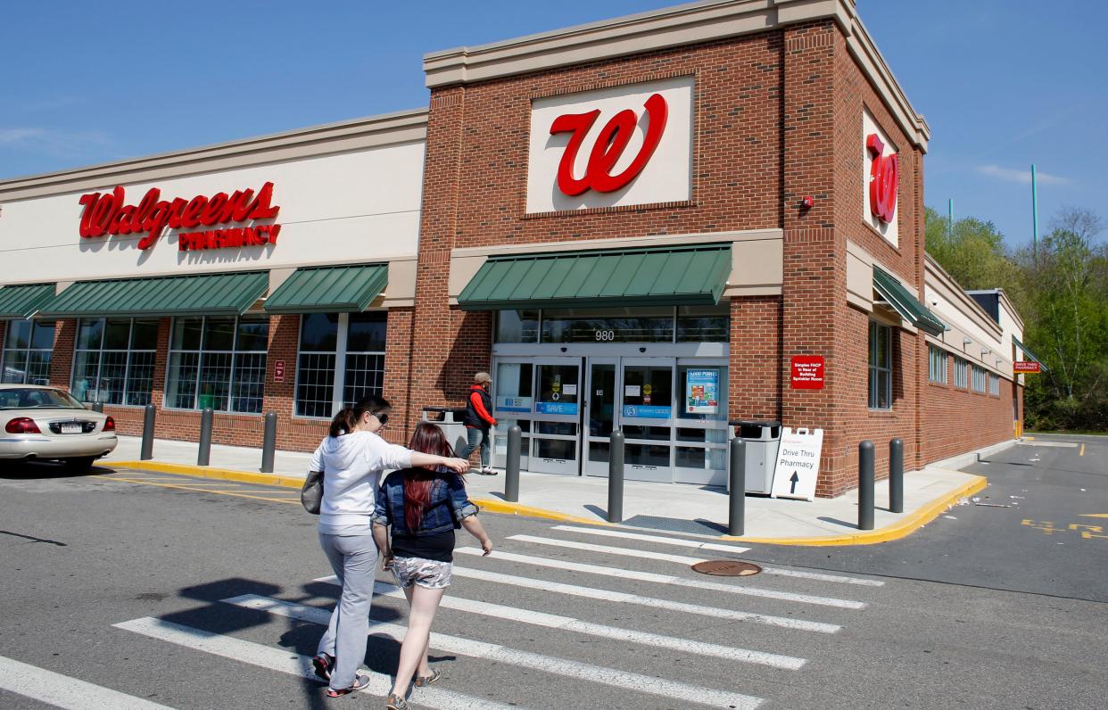 In this Wednesday, May 14, 2014, file photo, customers walk toward an entrance to a Walgreens store location, in Boston.