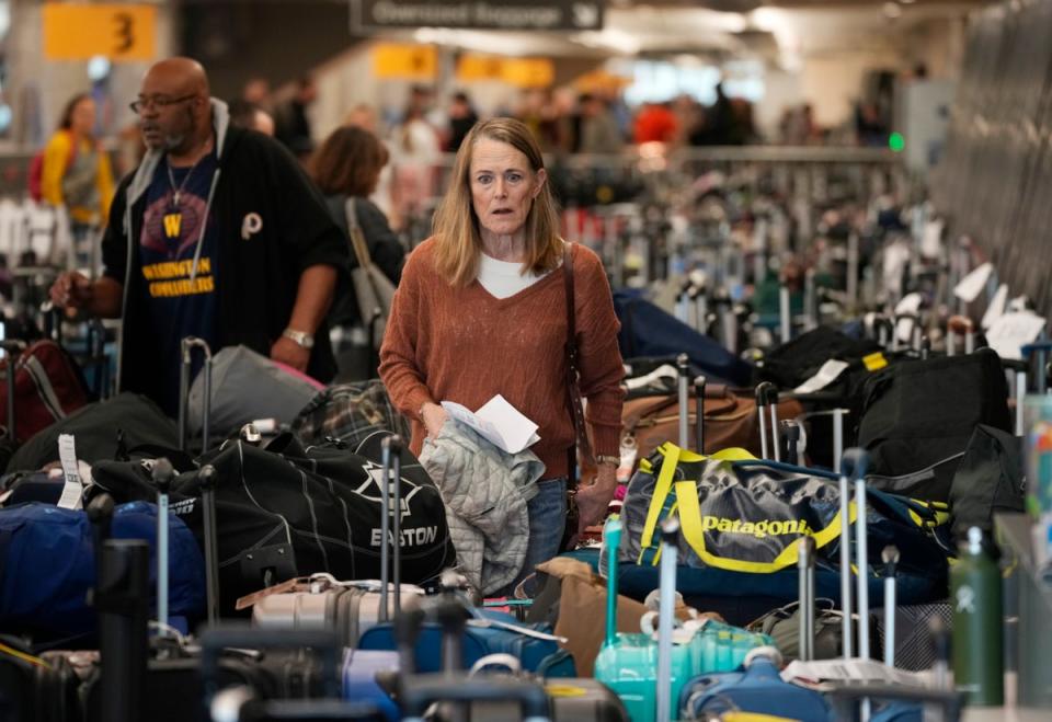 A passenger wades through a mountain of luggage amid thousands of Southwest Airlines cancellations (Copyright 2022 The Associated Press. All rights reserved.)