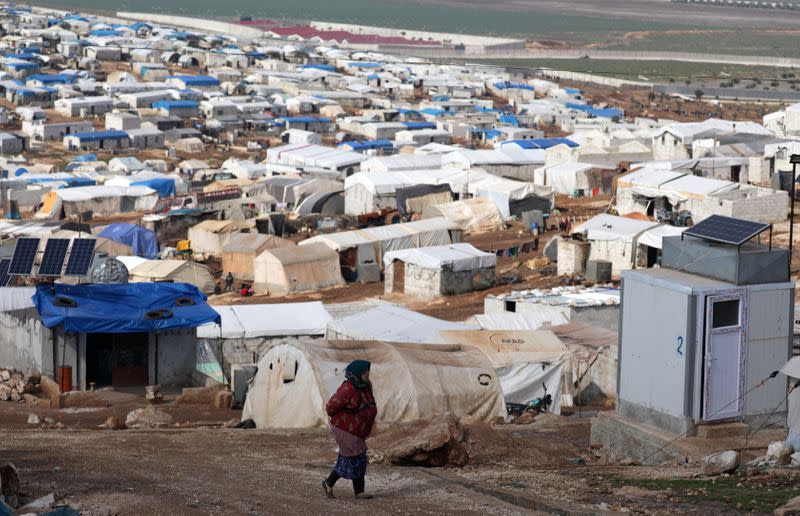An Internally displaced Syrian woman walks at Atmah IDP camp, located near the border with Turkey