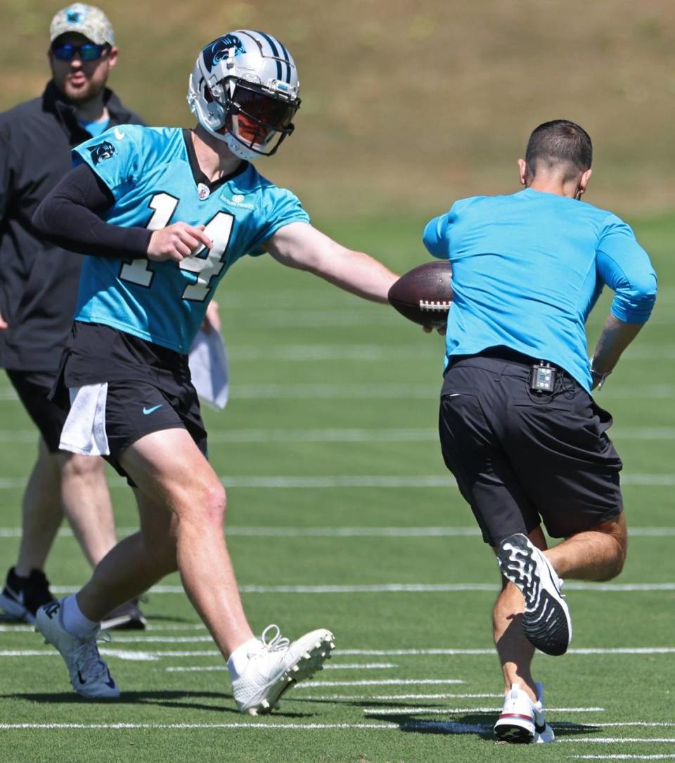 Carolina Panthers quarterback Andy Dalton, left, hands the ball off to head coach Dave Canales, right, during the team’s voluntary minicamp practice on Tuesday, April 23, 2024.