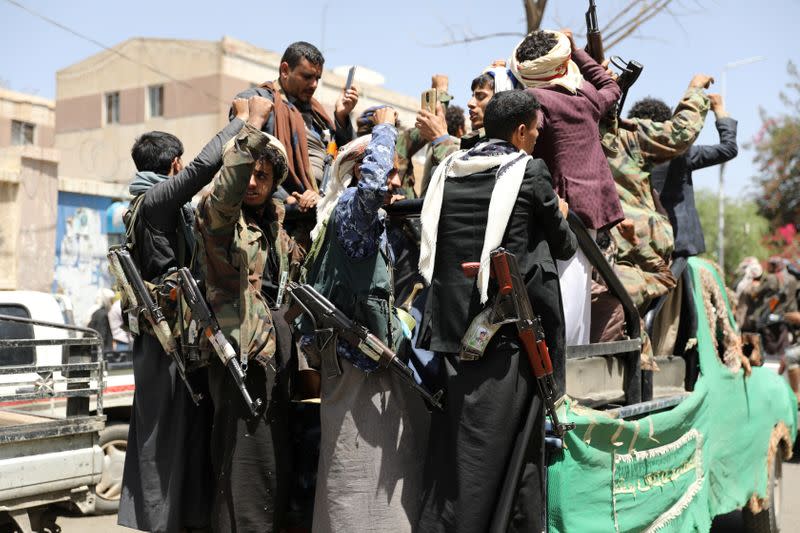 Armed Houthi followers ride on the back of a truck outside a hospital in Sanaa