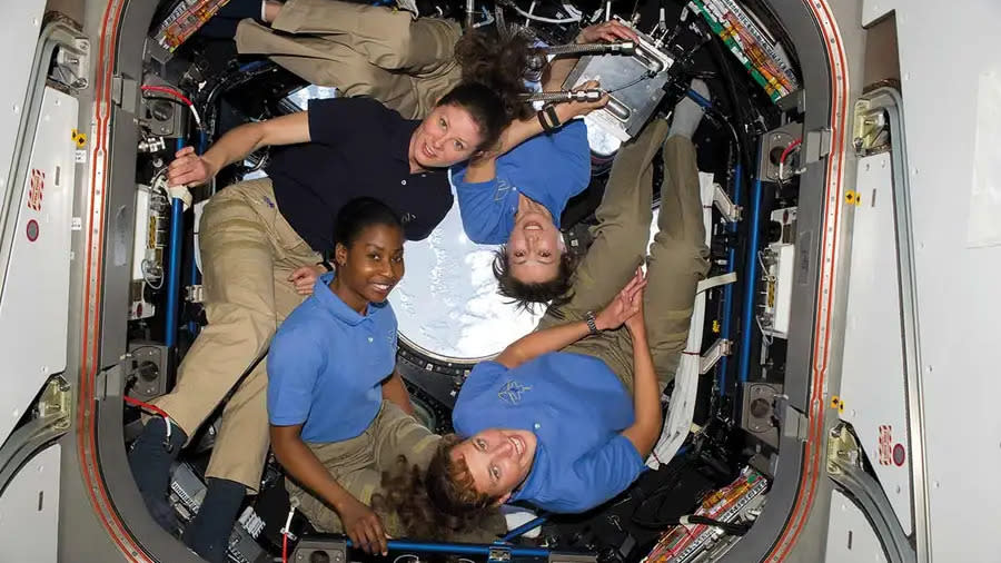  4 women in the international space station smiling at the camera. 