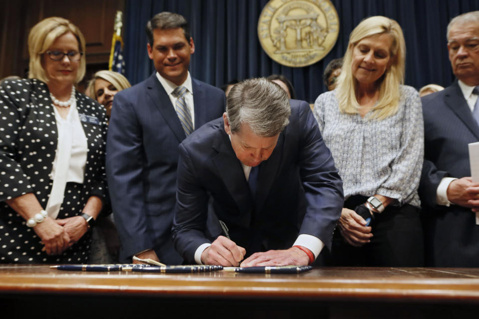 FILE - In this May 7, 2019, file photo, Georgia's Republican Gov. Brian Kemp, center, signs legislation in Atlanta, banning abortions once a fetal heartbeat can be detected. Opponents of a Georgia law that bans most abortions are asking a judge Tuesday, July 23, 2019, to keep it from taking effect while a legal challenge plays out. The law is set to become enforceable Jan. 1. Lawyers with the American Civil Liberties Union, Planned Parenthood and the Center for Reproductive Rights sued last month on behalf of Georgia advocacy groups and abortion providers to challenge the measure. (Bob Andres/Atlanta Journal-Constitution via AP, File)