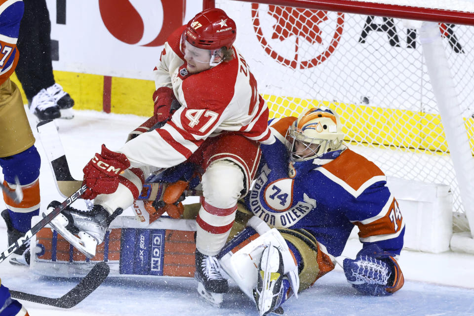 Calgary Flames' Connor Zary falls onto Edmonton Oilers goalie Stuart Skinner during the second period of an NHL hockey game Saturday, Jan. 20, 2024, in Calgary, Alberta. (Larry MacDougal/The Canadian Press via AP)