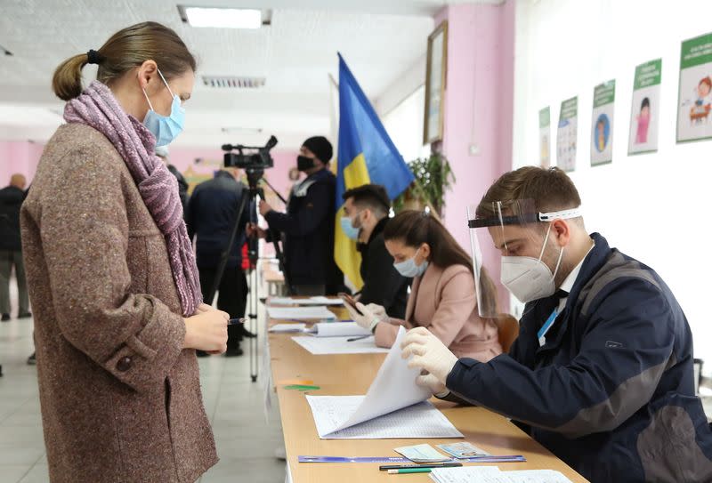 An election official checks a voter's information at a polling station during the second round of a presidential election in Chisinau
