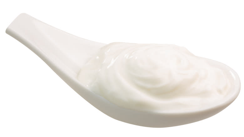 Thick cream on white spoon against white background