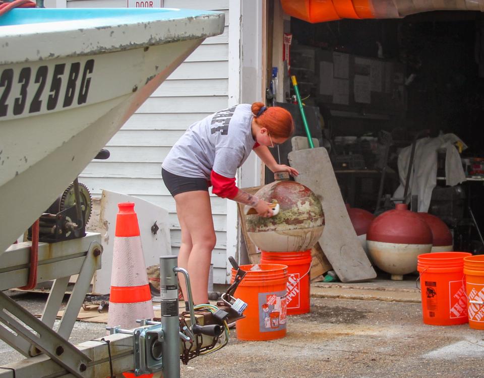 Autumn Tessier cleans a mooring ball in preparation for repainting it, at Greater Fall River Re-Creation's sailing center at Heritage State Park in Fall River.