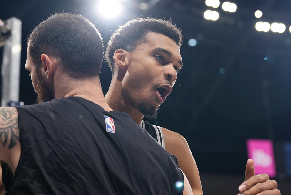 San Antonio Spurs center Victor Wembanyama, right, greets forward Sandro Mamukelashvili before the team's NBA basketball game against the Denver Nuggets on Tuesday, April 2, 2024, in Denver. (AP Photo/David Zalubowski)