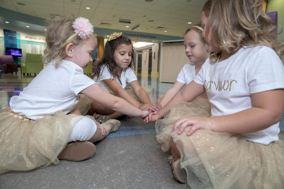 In this photo provided by Johns Hopkins All Children’s Hospital, Lauren Glynn, Chloe Grimes, McKinley Moore and Avalynn Luciano place their hands together at the hospital in St. Petersburg, Fla., Aug. 9, 2018. The girls, who were diagnosed with cancer in 2016 and became fast friends while undergoing treatment, reunite every year. (Allyn DiVito/John Hopkins All Children's Hospital via AP)