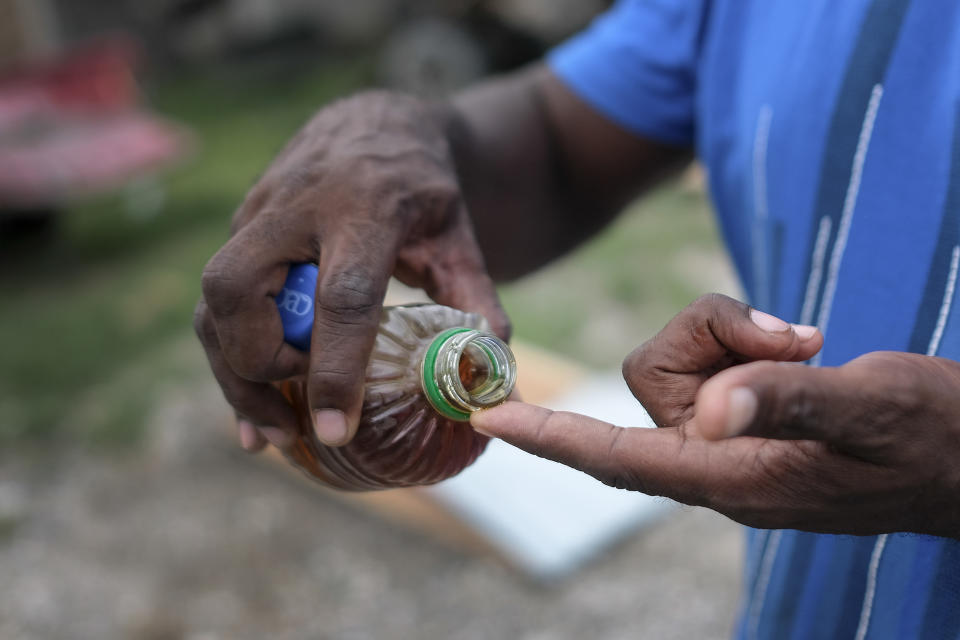 Kurtch Jeune, owner of the Etheuss company, shows vetiver oil refined at his factory that was made inoperable by the 7.2 magnitude earthquake in Les Cayes, Haiti, Thursday, Aug. 19, 2021. Many of the factories that contributed to one of Haiti's top exporter used in fine perfumes, cosmetics, soaps and aromatherapy, are now inoperable. (AP Photo/Matias Delacroix)