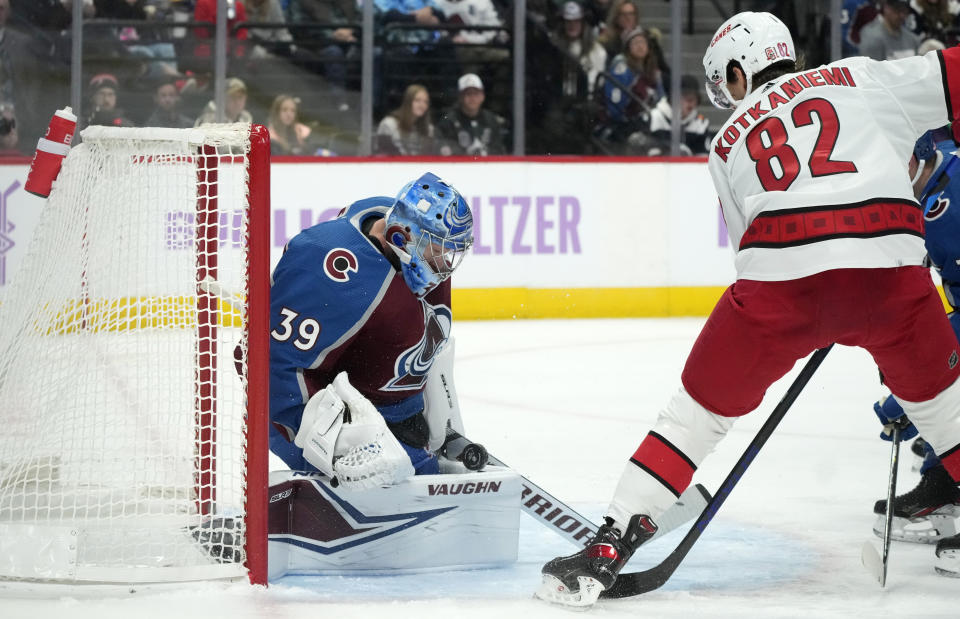 Colorado Avalanche goaltender Pavel Francouz, left, stops a redirected shot off the stick of Carolina Hurricanes center Jesperi Kotkaniemi (82) in the second period of an NHL hockey game Saturday, Nov. 12, 2022, in Denver. (AP Photo/David Zalubowski)