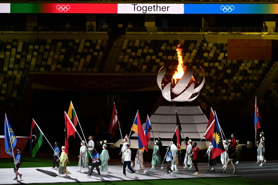 <p>Athletes delegations walk past the Olympic cauldron with their national flag as they enter during the closing ceremony of the Tokyo 2020 Olympic Games, at the Olympic Stadium, in Tokyo, on August 8, 2021. (Photo by Jewel SAMAD / AFP) (Photo by JEWEL SAMAD/AFP via Getty Images)</p> 