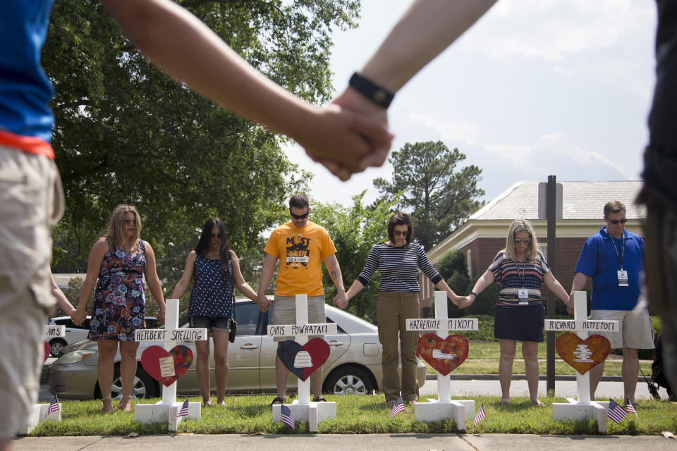 Community members hold hands and pray around the 12 crosses at the memorial located by Building 11 of the Municipal Center, June 2, 2019, in Virginia Beach, Va. (Photo: Sarah Holm/The Virginian-Pilot via AP)