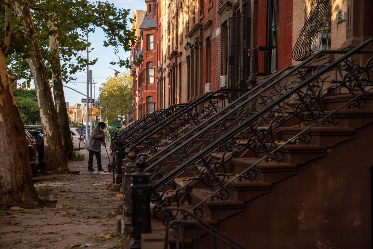 A person sweeps up debris in the front of a brownstone after the extremely heavy rainfall from Hurricane Ida on Sept. 2, 2021, in the Bronx borough of New York City.