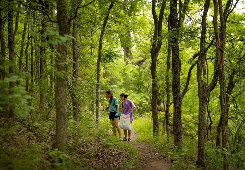 Annie Scroggs, left, and Catie McGill, pick up litter on the Zilker Nature Preserve Trail on April 22, 2022. They were participating in the Rowing Dock Kayak Cleanup Crew’s Earth Day Lake Cleanup. (Credit: Jay Janner/American-Statesman)