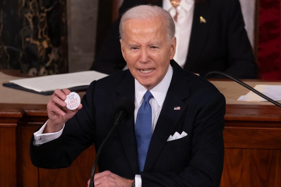 President Joe Biden holds up a pin referring to murdered Georgia student Laken Riley while delivering his State of the Union address (EPA)